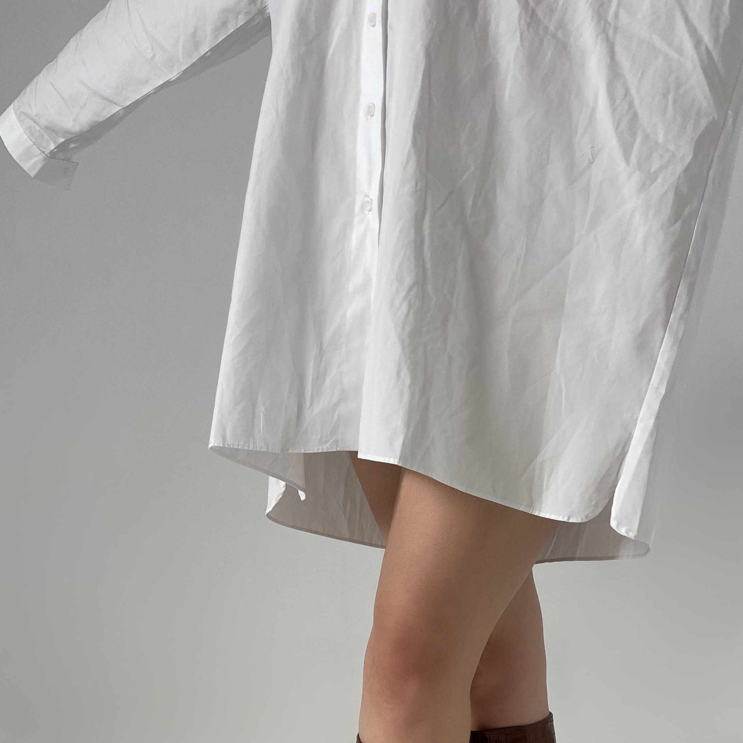 vue des jambes d'une femme portant une chemise blanche oversize comme si c'était une robe