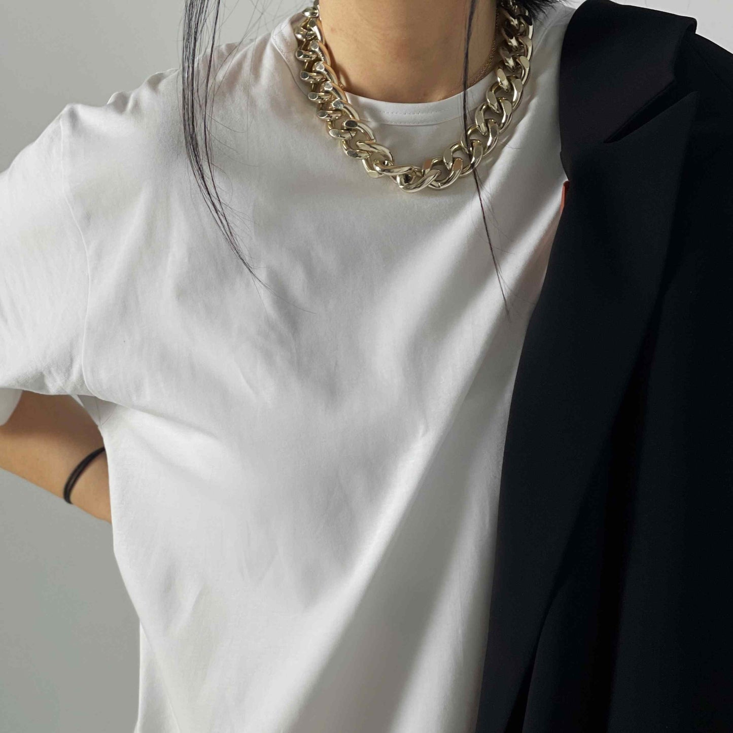 buste d'une femme habillé d'un tee-shirt blanc oversize en coton et d'un collier en or